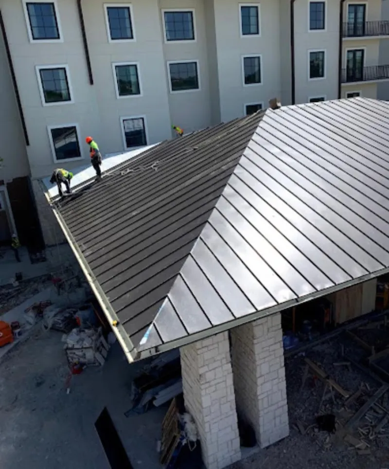 Crew installing standing seam metal roof panels on a commercial project in Tipp City